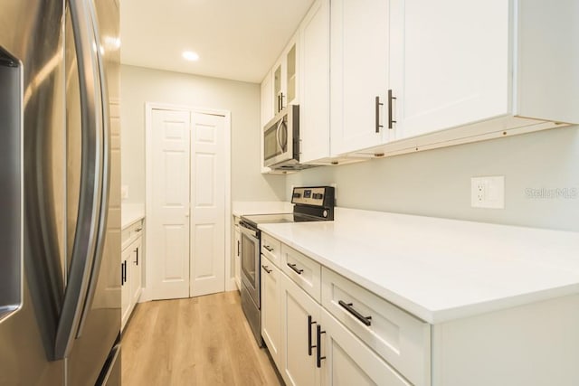 4230 Ponds Dr, Cocoa, FL 32927 - kitchen featuring stainless steel appliances, light wood-style flooring, recessed lighting, white cabinets, and light countertops