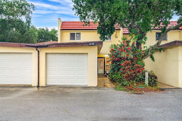 view of front of property featuring driveway, a tile roof, and stucco siding