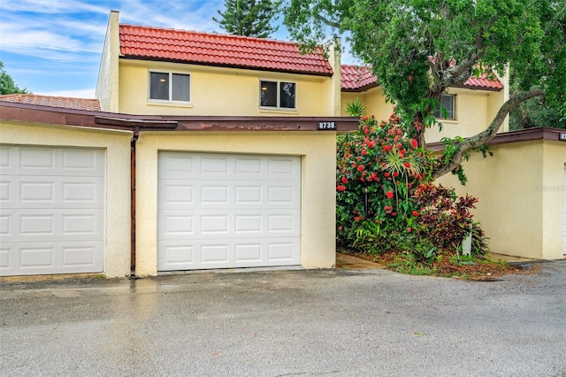 view of front of house with a garage, a tile roof, and stucco siding