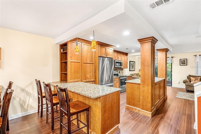 kitchen with visible vents, appliances with stainless steel finishes, brown cabinets, a peninsula, and ornate columns