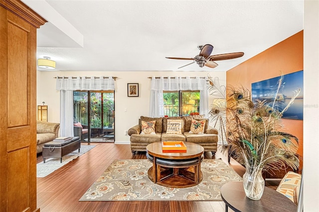 living area featuring plenty of natural light, a textured ceiling, a ceiling fan, and wood finished floors