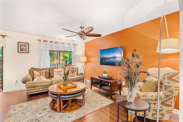 living area with wood finished floors, a ceiling fan, and baseboards