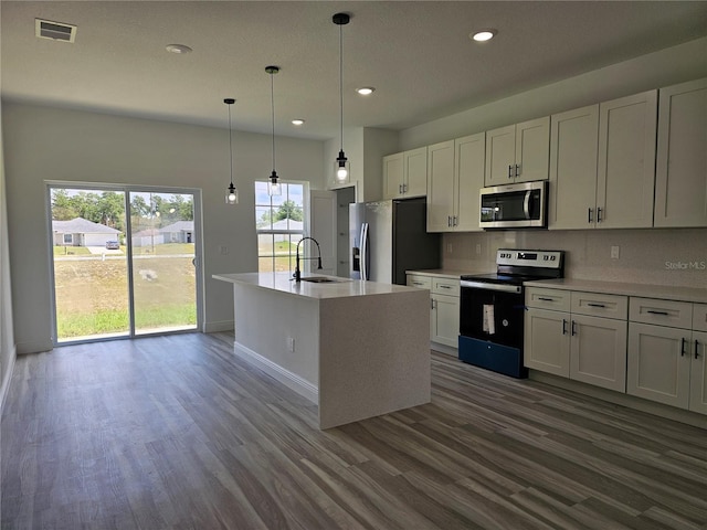 kitchen featuring tasteful backsplash, appliances with stainless steel finishes, dark hardwood / wood-style floors, and a kitchen island with sink