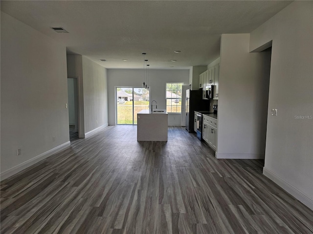 kitchen with white cabinetry, pendant lighting, an island with sink, and dark wood-type flooring