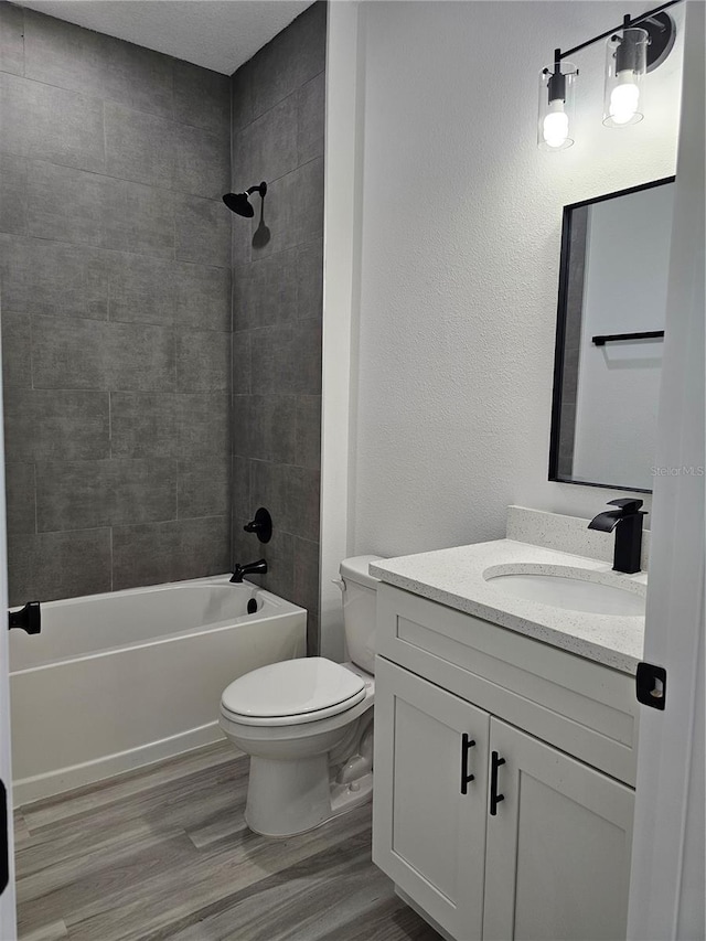 full bathroom featuring tiled shower / bath, vanity, toilet, and hardwood / wood-style floors