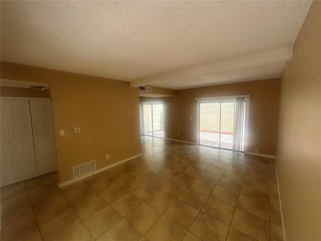 tiled empty room with a textured ceiling