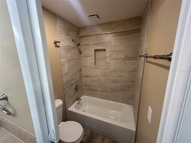 bathroom with tiled shower / bath, hardwood / wood-style flooring, and toilet