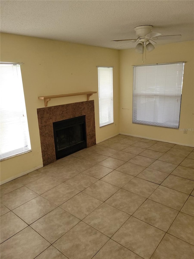 unfurnished living room featuring plenty of natural light, ceiling fan, light tile patterned floors, and a fireplace