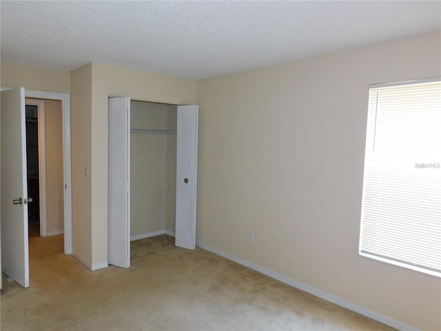 unfurnished bedroom with multiple windows, light carpet, and a closet