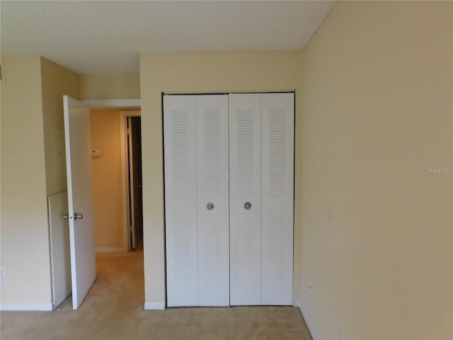 unfurnished bedroom with a closet and light carpet