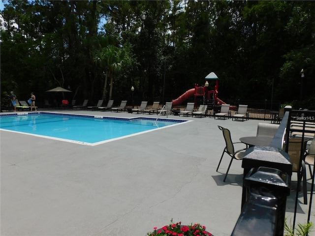 view of pool with a playground and a patio area