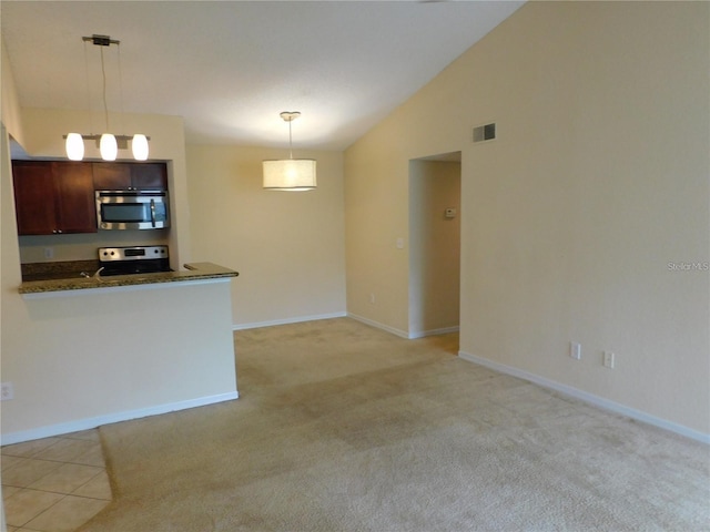 kitchen featuring vaulted ceiling, decorative light fixtures, stainless steel appliances, dark brown cabinets, and light carpet