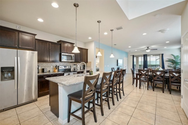 kitchen with backsplash, ceiling fan, an island with sink, appliances with stainless steel finishes, and sink