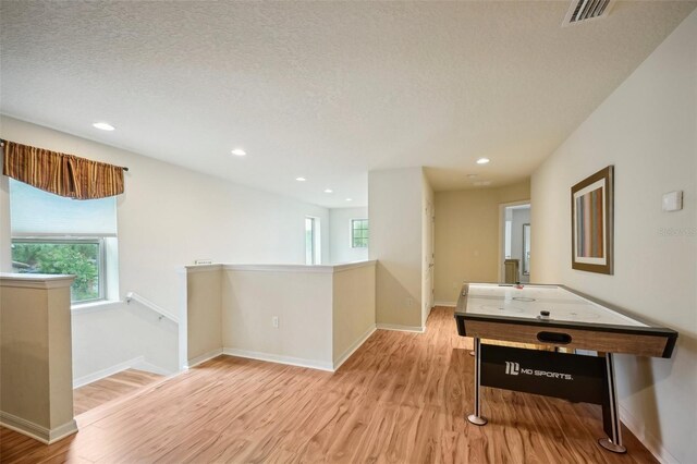 rec room with a textured ceiling and light wood-type flooring