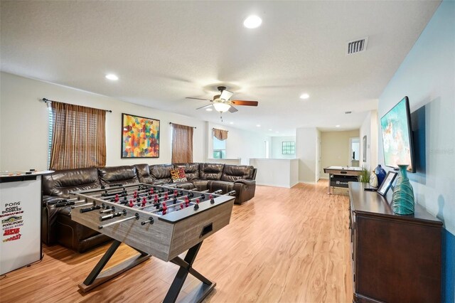 game room featuring ceiling fan, light hardwood / wood-style floors, and a textured ceiling