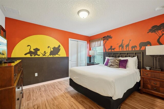 bedroom with a closet, light hardwood / wood-style floors, and a textured ceiling