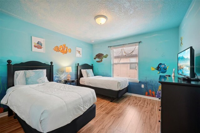 bedroom with a textured ceiling and wood-type flooring