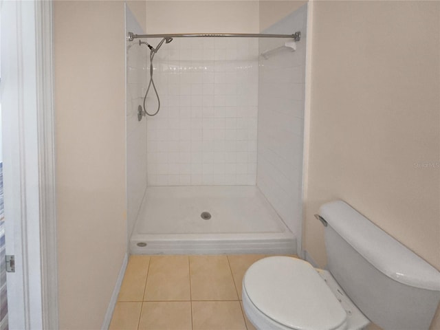 bathroom featuring tile patterned floors, toilet, and tiled shower