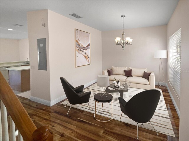 living room featuring a notable chandelier, dark wood-type flooring, and electric panel