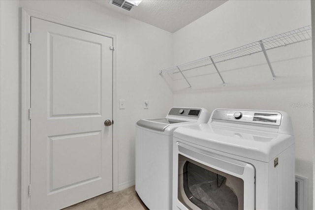 laundry area featuring washer and clothes dryer and light tile floors