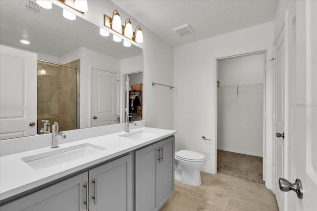 bathroom with vanity with extensive cabinet space, dual sinks, toilet, tile floors, and a textured ceiling