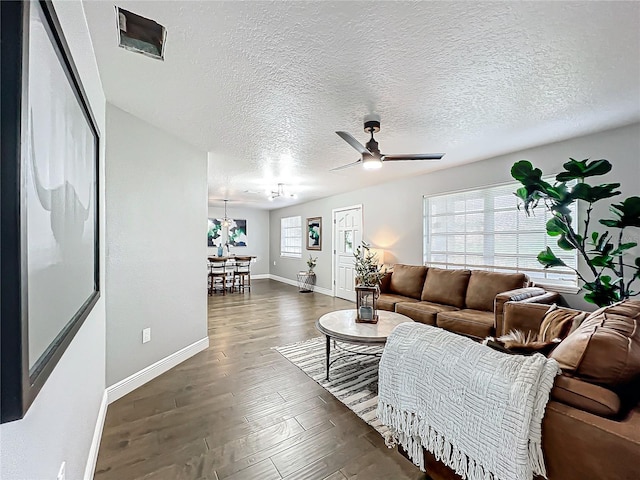 living room with a textured ceiling, plenty of natural light, dark wood-type flooring, and ceiling fan