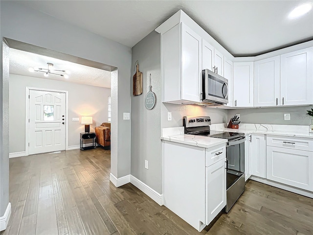 kitchen with light stone counters, hardwood / wood-style floors, white cabinets, and stainless steel appliances