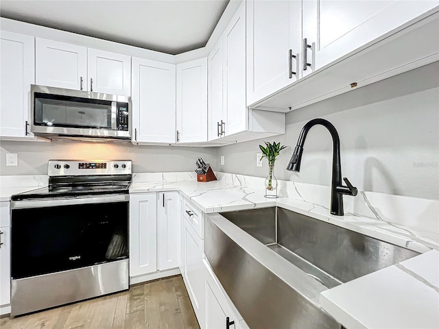 kitchen with white cabinets, stainless steel appliances, light hardwood / wood-style floors, and sink