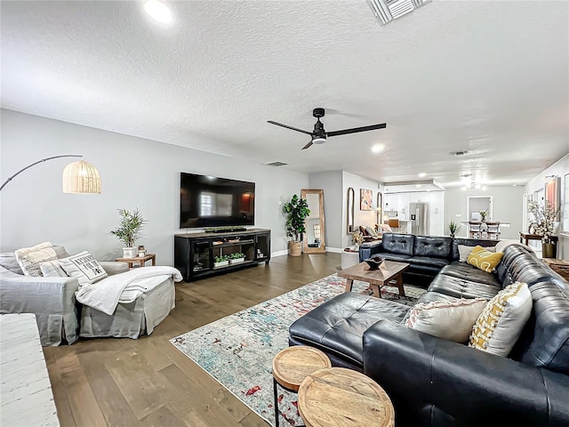 living room featuring a textured ceiling, hardwood / wood-style flooring, and ceiling fan