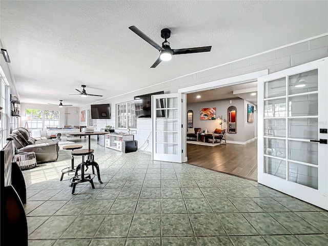 tiled living room featuring ceiling fan, a textured ceiling, and french doors