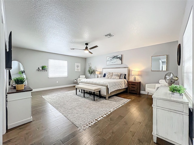 bedroom featuring ceiling fan, dark hardwood / wood-style floors, and a textured ceiling