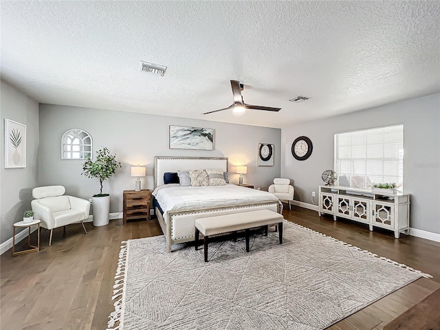 bedroom with ceiling fan, dark hardwood / wood-style floors, and a textured ceiling