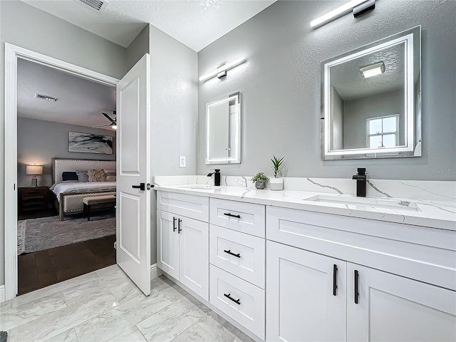 bathroom with a textured ceiling, vanity, and ceiling fan