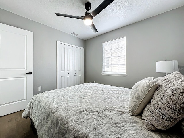 bedroom featuring ceiling fan, a closet, hardwood / wood-style floors, and a textured ceiling