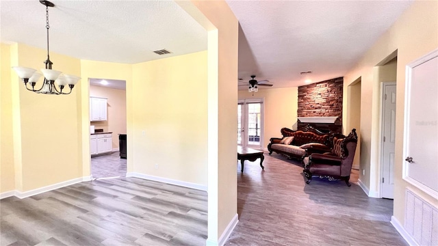 corridor with a textured ceiling, french doors, a notable chandelier, and light hardwood / wood-style floors