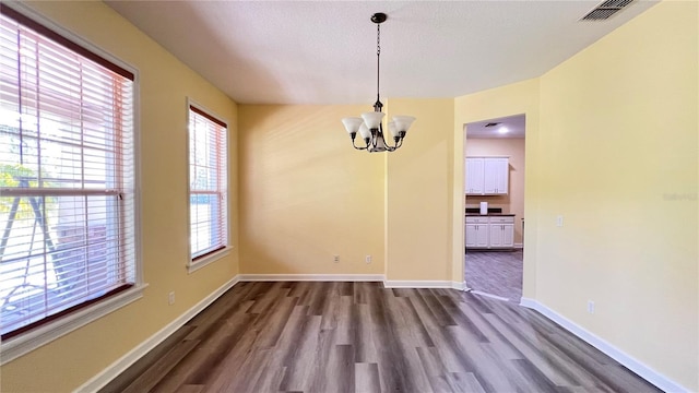 unfurnished dining area with dark hardwood / wood-style floors and a notable chandelier