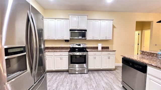 kitchen featuring light hardwood / wood-style flooring, stainless steel appliances, dark stone counters, and white cabinets