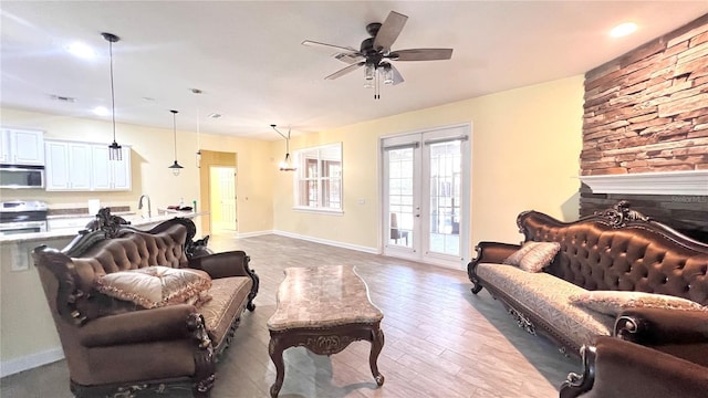 living room featuring a fireplace, hardwood / wood-style flooring, sink, and ceiling fan