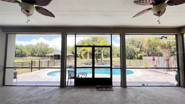 doorway to outside featuring ceiling fan, concrete floors, and a textured ceiling