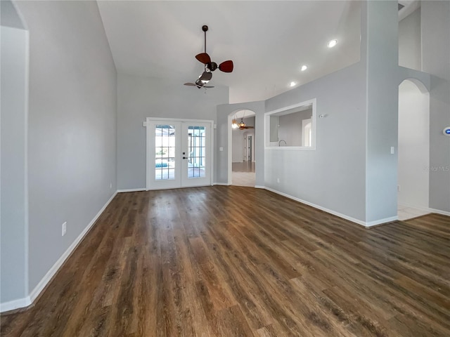 unfurnished living room with ceiling fan, a towering ceiling, dark hardwood / wood-style flooring, and french doors