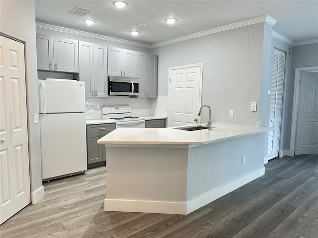 kitchen with sink, backsplash, ornamental molding, kitchen peninsula, and white appliances