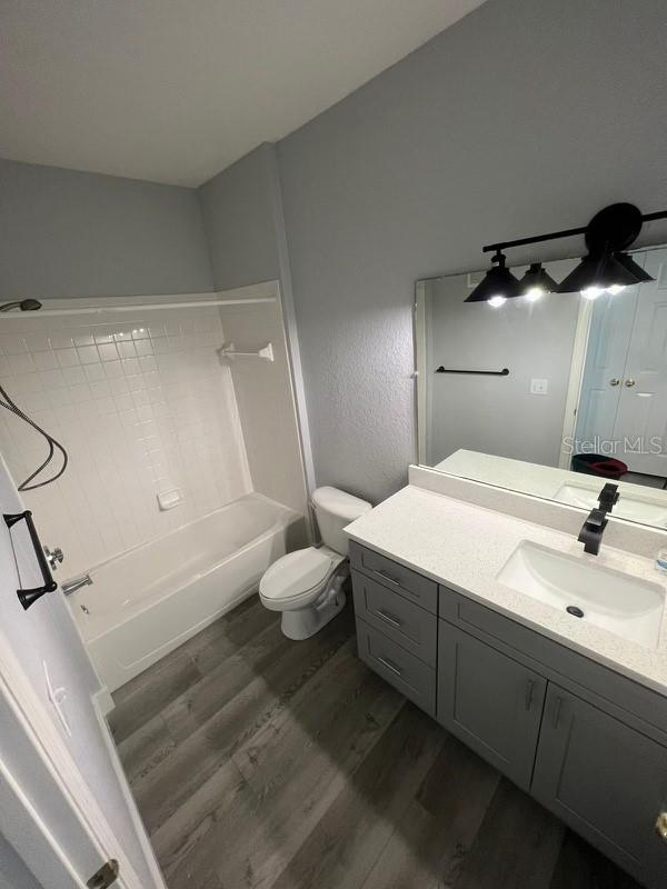 full bathroom featuring toilet, shower / tub combination, vanity, hardwood / wood-style flooring, and ceiling fan