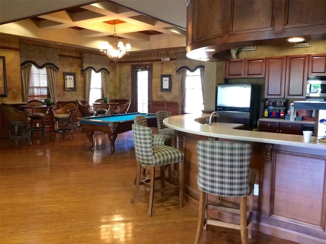 interior space with pendant lighting, a chandelier, hardwood / wood-style flooring, coffered ceiling, and stainless steel appliances