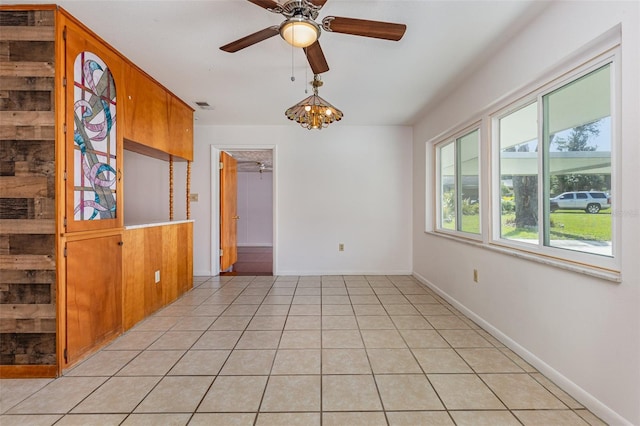 unfurnished dining area featuring ceiling fan with notable chandelier and light tile patterned flooring