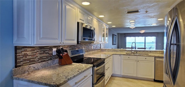 kitchen featuring sink, tasteful backsplash, light tile patterned flooring, white cabinets, and appliances with stainless steel finishes