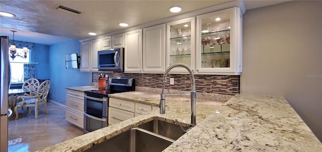 kitchen featuring decorative backsplash, appliances with stainless steel finishes, white cabinetry, and hanging light fixtures