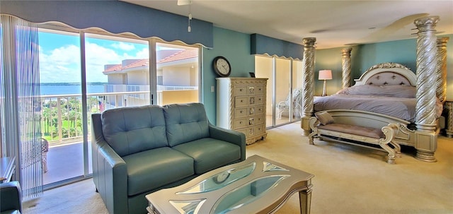 bedroom featuring access to exterior, a water view, and light colored carpet