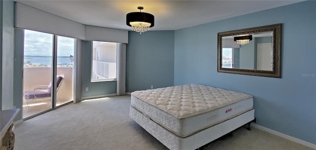 bedroom with a chandelier, a water view, and light colored carpet