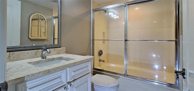 full bathroom featuring vanity, enclosed tub / shower combo, and toilet