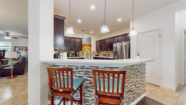 kitchen featuring ceiling fan, hanging light fixtures, stainless steel fridge with ice dispenser, kitchen peninsula, and decorative backsplash